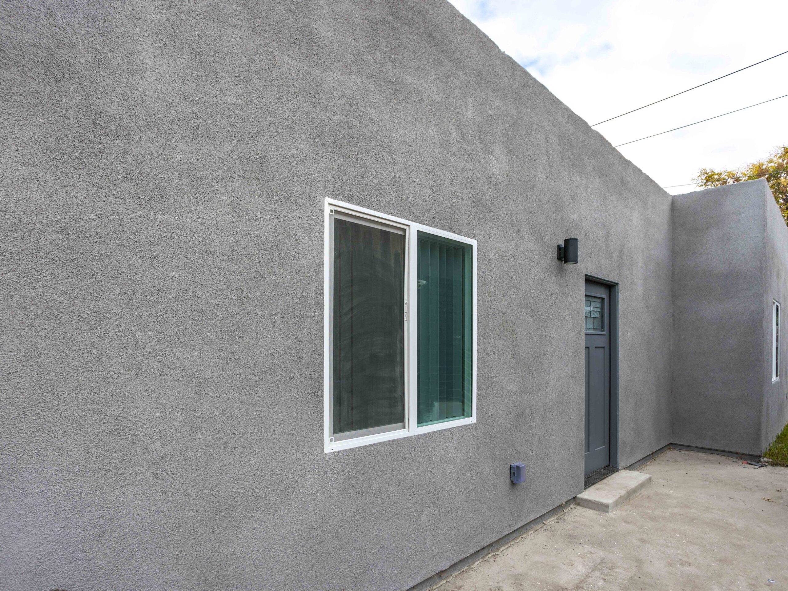 Rear corner of the converted garage with new window openings and finished stucco