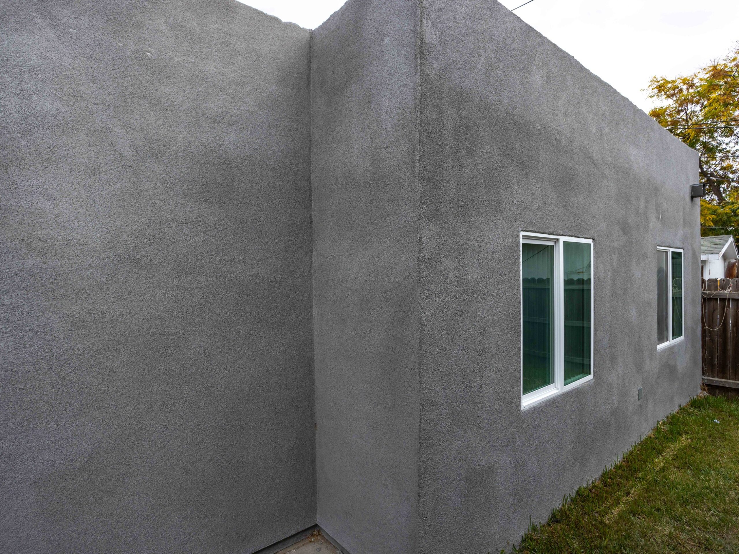 Side elevation of the converted garage showing the flat parapet roofline and a level path to the entry