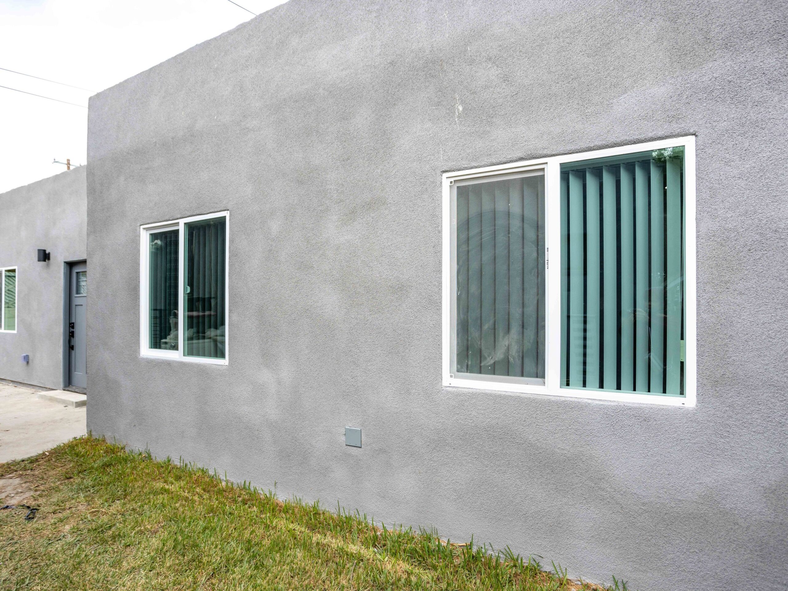 New windows cut into the block wall of a converted garage, with matching stucco reveals