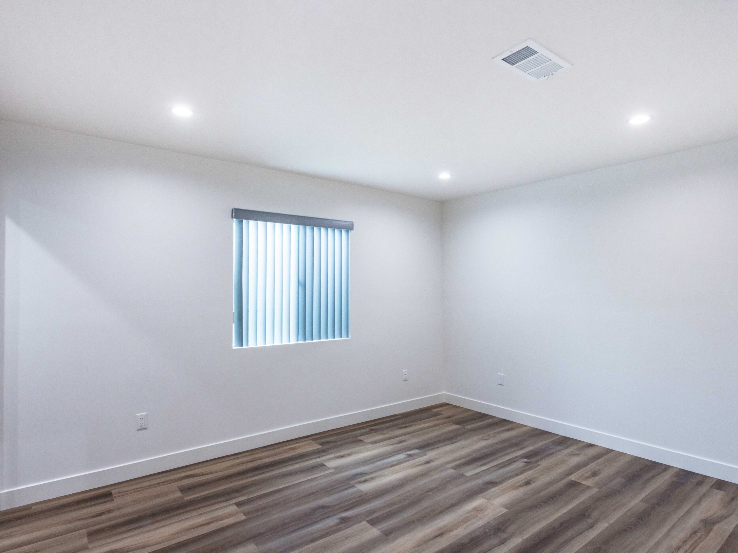Finished living space inside the converted garage with a level plank floor, boarded walls and recessed lighting