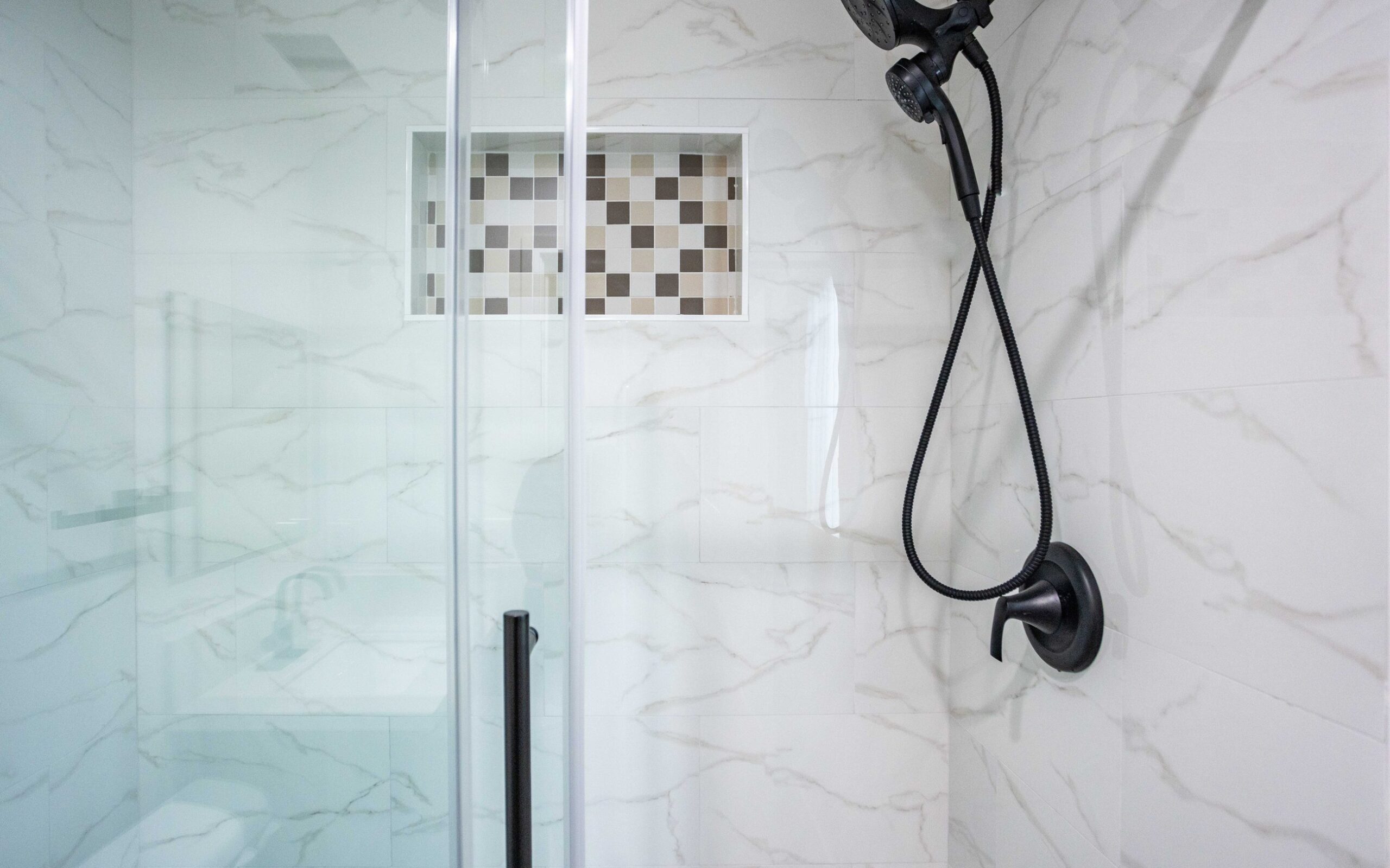 Frameless glass shower with tiled walls and a mosaic floor in the converted unit