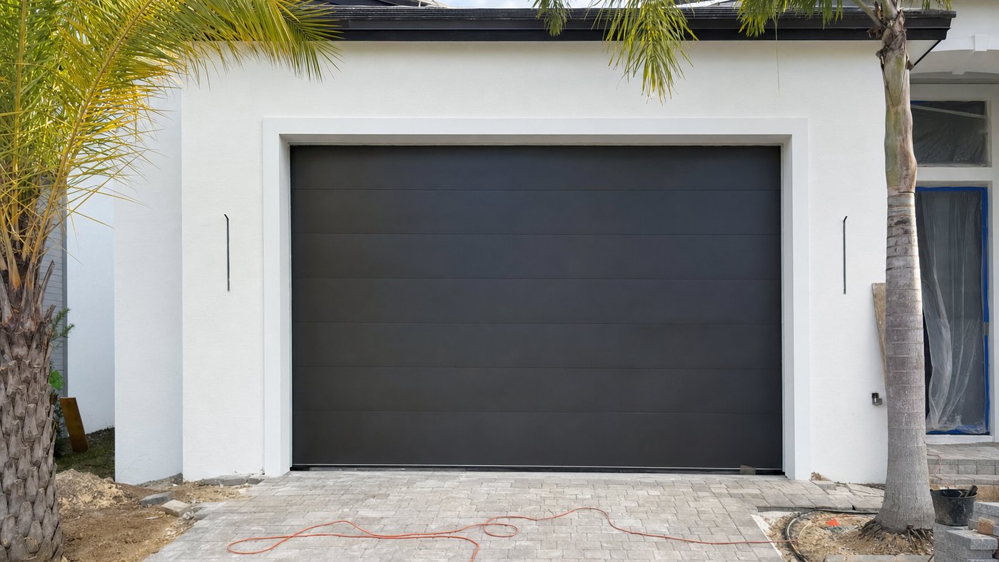 Illustration of a newly installed insulated sectional garage door in a white stucco opening on a South Florida house