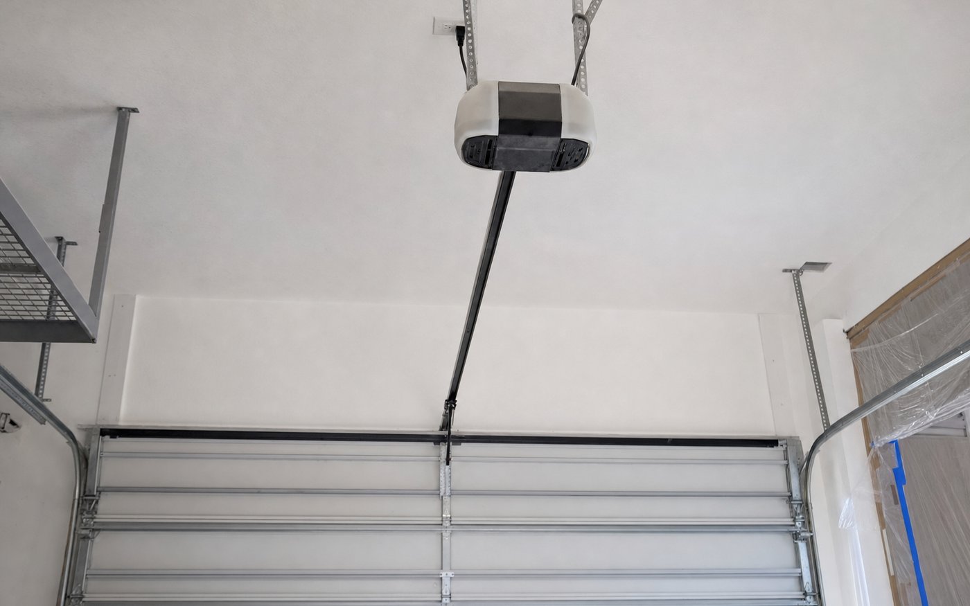Illustration of a ceiling-mounted garage door opener with its rail and arm connected to the top panel