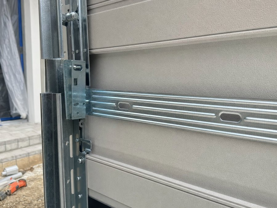 Illustration of the inside face of a garage door panel showing the horizontal reinforcing strut and bracket
