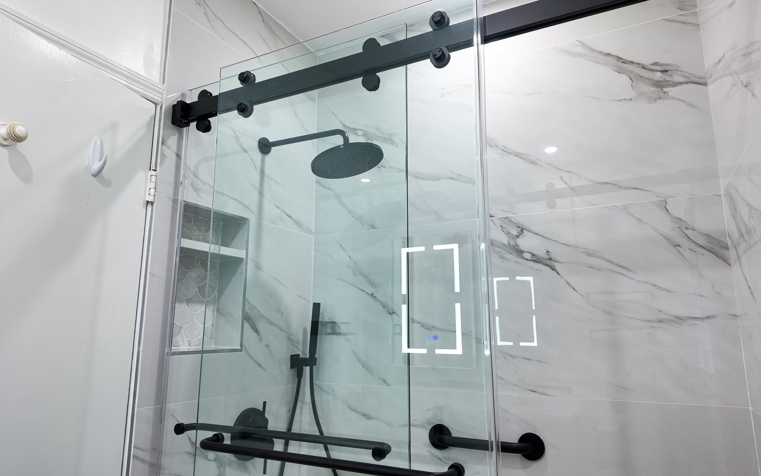 Frameless sliding shower screen on an exposed matt black track