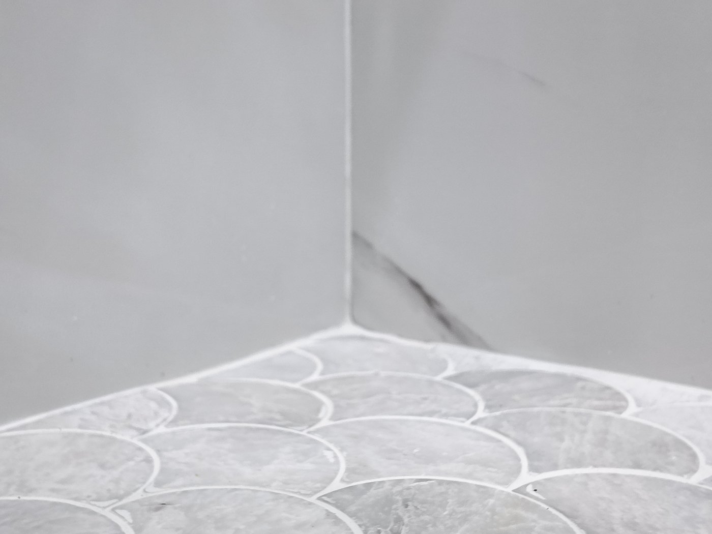 Scalloped marble-look mosaic shower floor falling to a linear drain