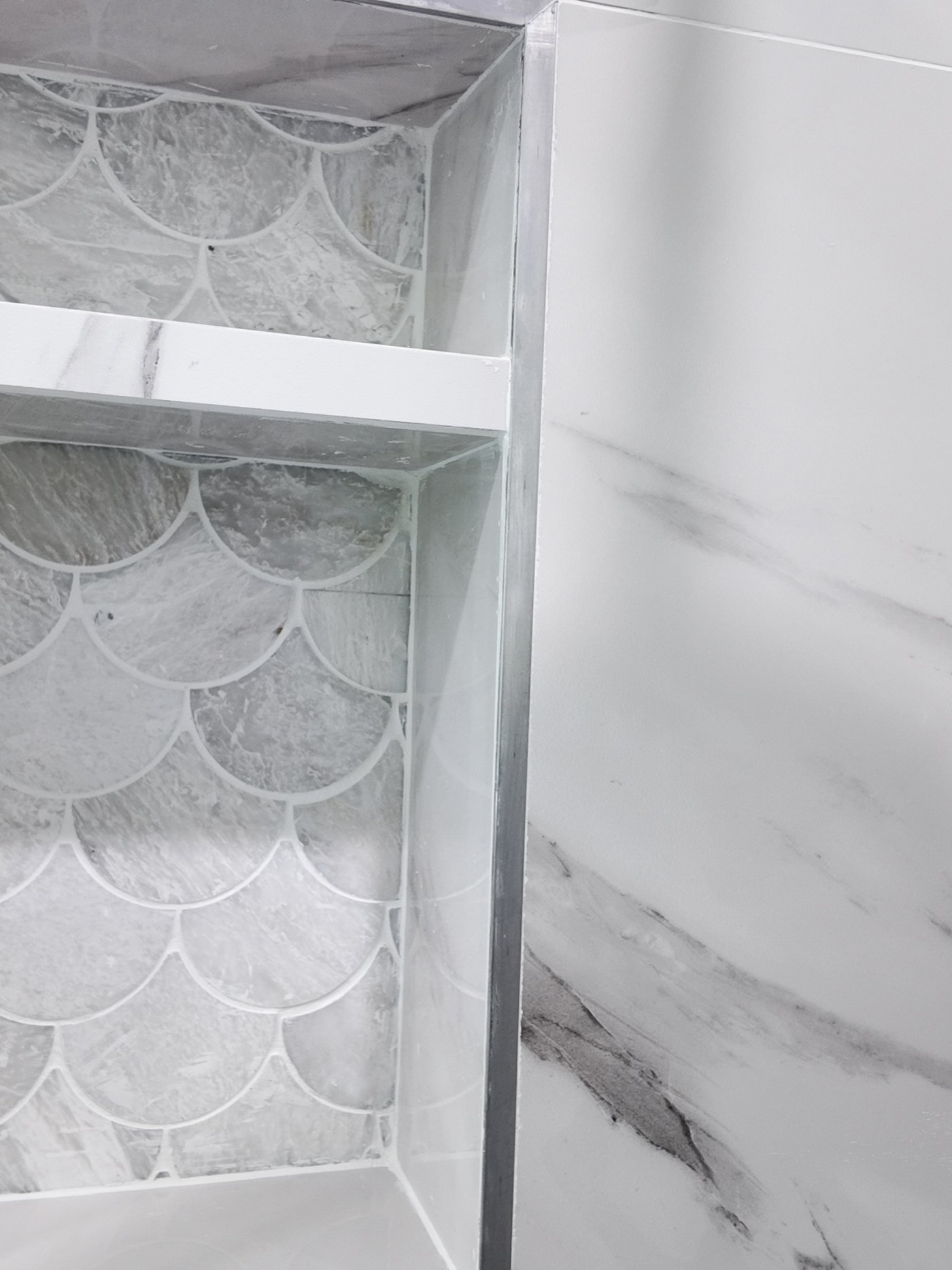 Recessed shower niche finished in the same porcelain with a metal trim edge