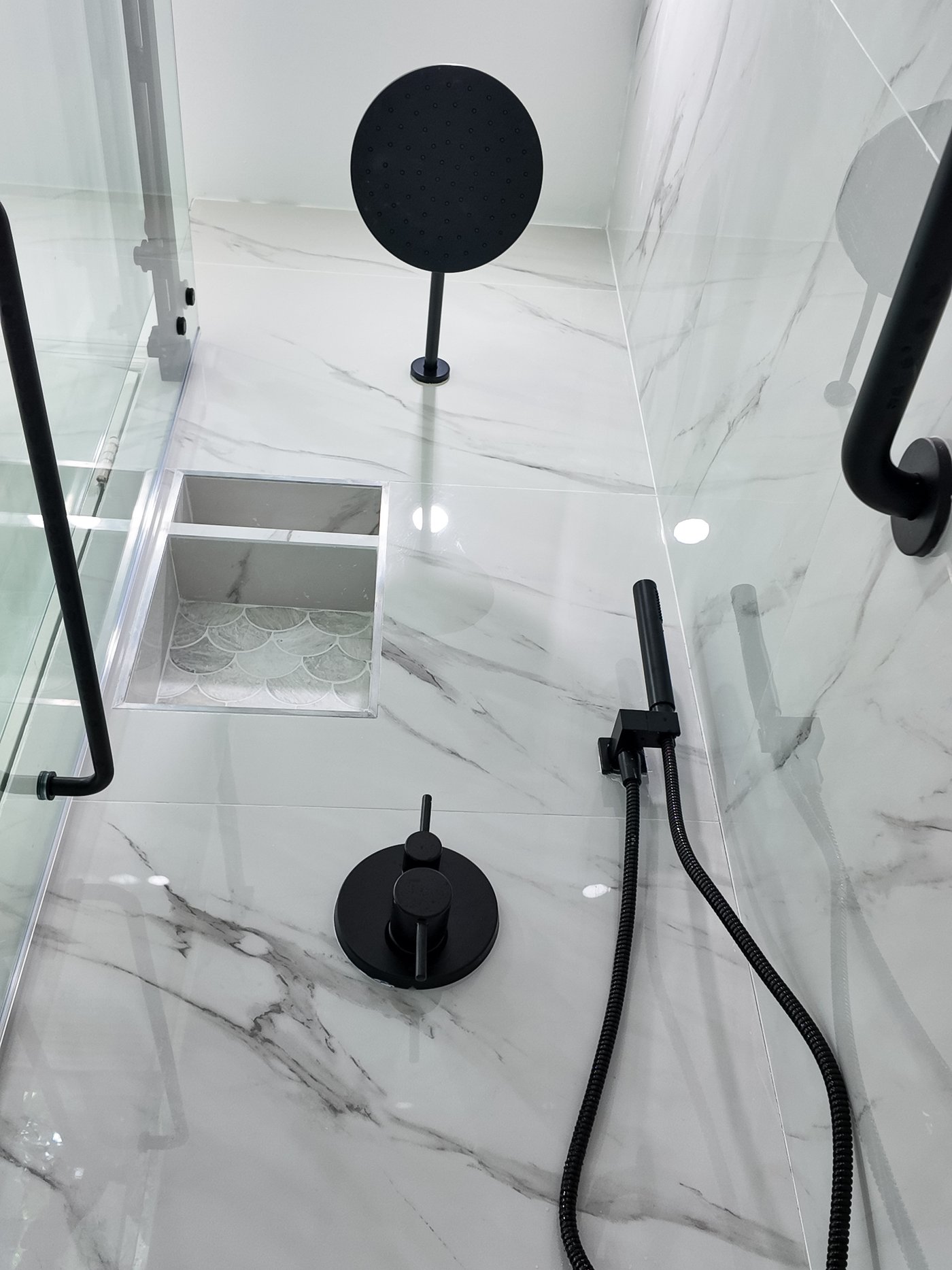 Matt black thermostatic shower valve, hand shower on a rail and grab rail against porcelain