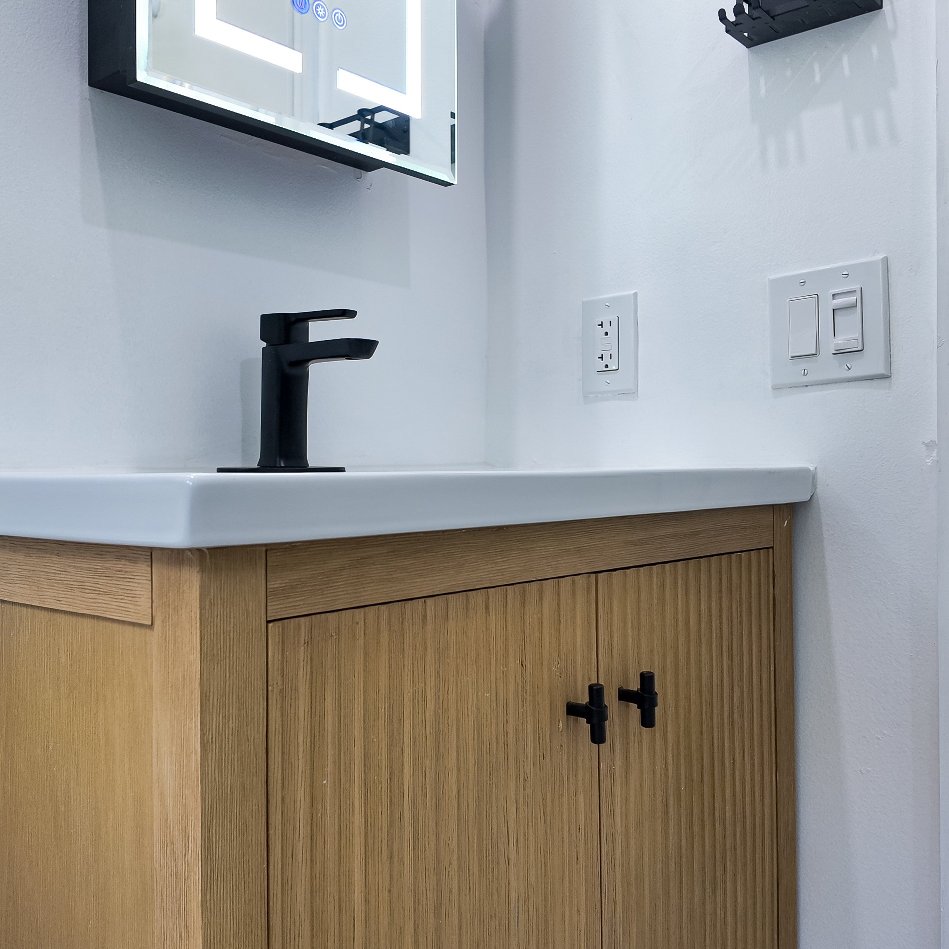 Close view of the fluted oak vanity front and its matt black handles