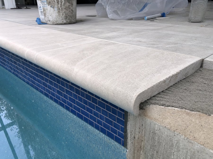Illustration of bullnose paver coping set at a pool edge with the overhang above the waterline visible
