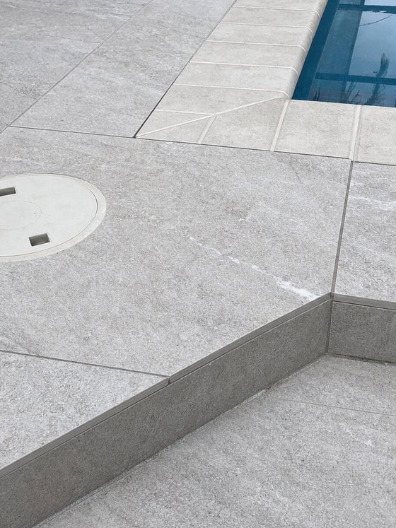 Illustration of pavers cut cleanly around a pool return fitting and a step corner