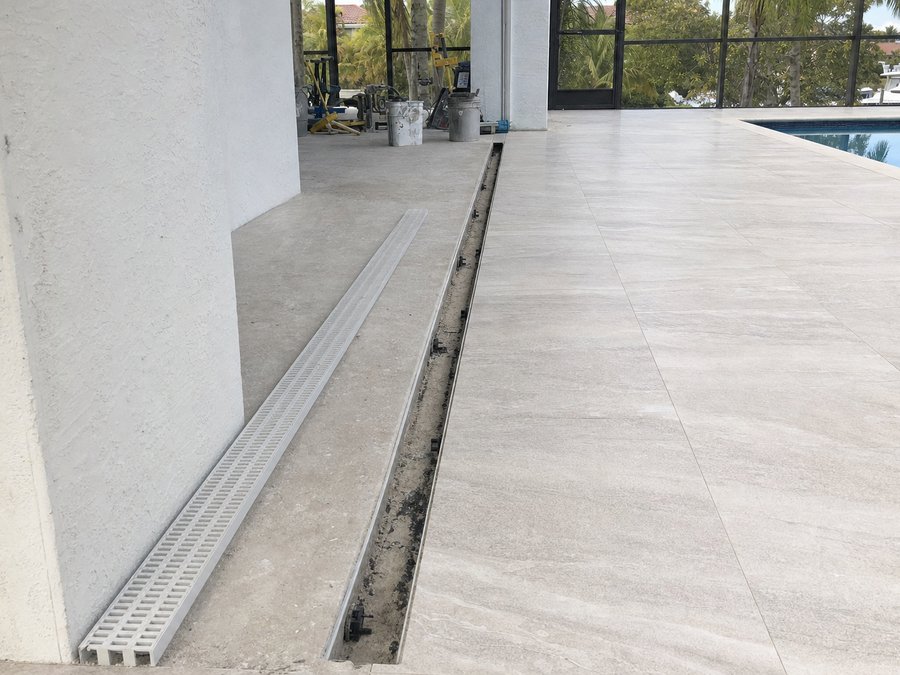 Illustration of a linear channel drain set into a paver deck between the pool coping and a house wall