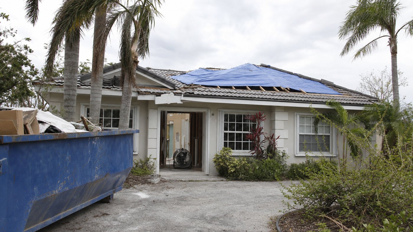 Illustration of a South Florida house under storm restoration with a secured tarpaulin over part of the roof