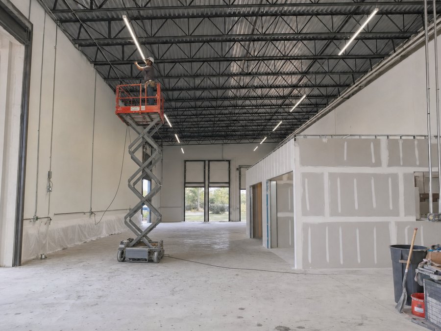Illustration of new linear high-bay LED fittings suspended from a warehouse roof structure