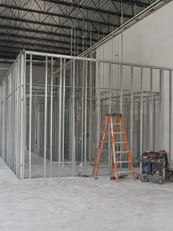 Illustration of light-gauge metal stud partitions being framed inside a warehouse to form an office area